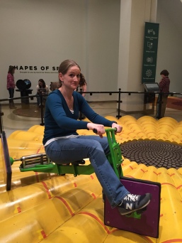 Mrs. Holm rides a square-wheeled tricycle at the Museum of Mathematics